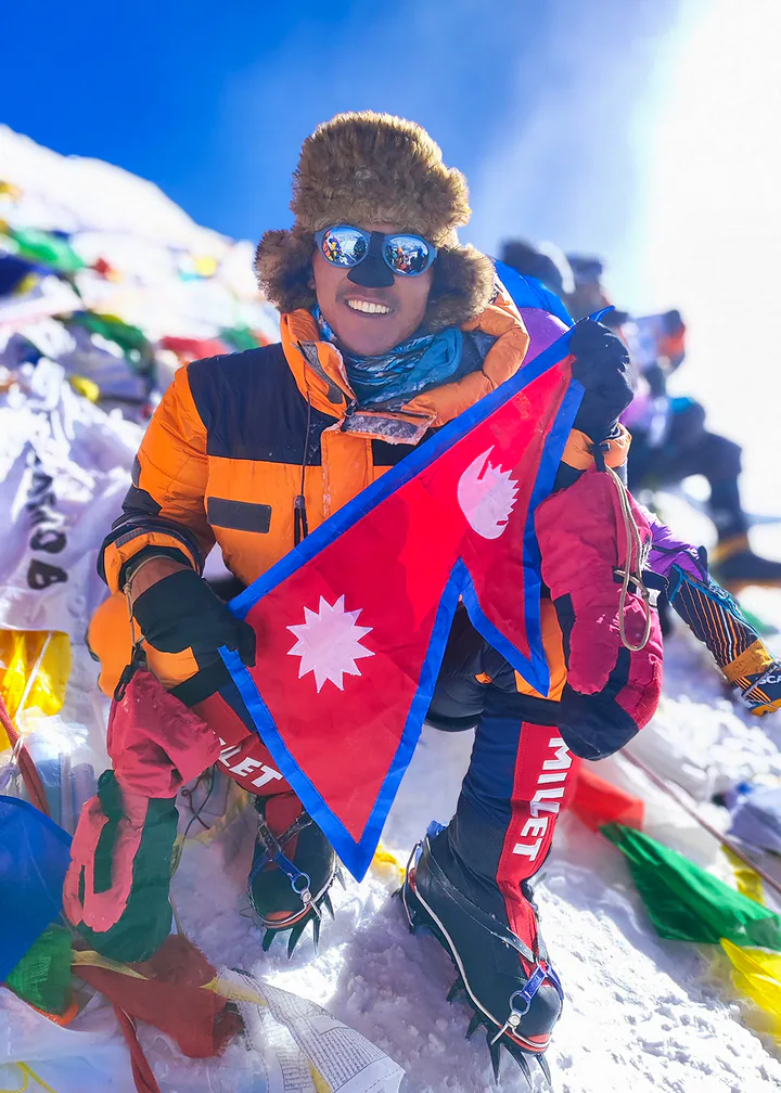 雪山を背景に立つネパール人登山ガイド